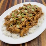 Crockpot Teriyaki Chicken with glossy homemade sauce over white rice and green onions