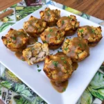 Golden turkey and stuffing cups topped with savory brown gravy and fresh parsley on a white serving plate